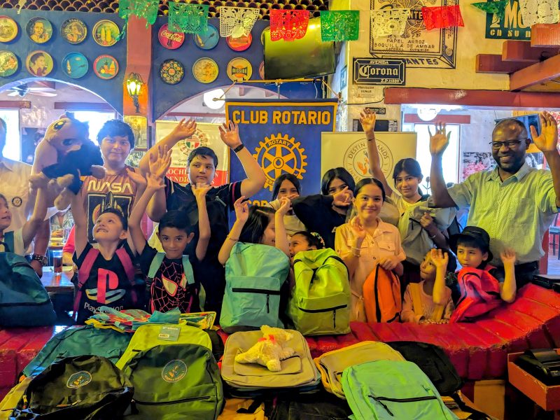 benefactors and children posing with donated backpacks