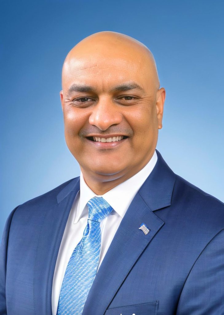 Headshot of Vinit Ahooja in blue suit with blue background